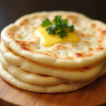 Freshly cooked Sourdough Discard Naan Bread with butter and cilantro, ready to enjoy.