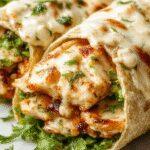 A close-up of a freshly assembled chicken Caesar wrap, featuring golden-brown toasted tortilla filled with tender chicken slices, crisp romaine lettuce, creamy Caesar dressing, and melted cheese oozing slightly at the edges, presented on a rustic wooden plate with fresh herbs scattered around.