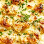 A golden-brown low carb chicken casserole served in a rustic ceramic dish garnished with fresh herbs. The casserole surface is crusty with melted cheese and tender chicken pieces visible around the edges, inviting a warm and hearty feel.
