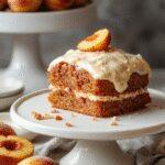 A slice of moist peach cake with a golden brown crust, topped with a generous swirl of brown sugar frosting and fresh peach slices, presented on a rustic white plate with delicate dessert forks nearby, steam gently rising from the warm cake.