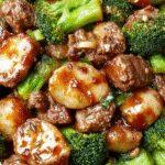 A vibrant stir-fry featuring tender ground beef and bright green broccoli florets coated in a glossy honey garlic sauce, plated neatly on a white dish with steam rising, set against a rustic wooden table background.