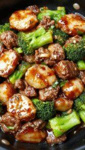 A vibrant stir-fry featuring tender ground beef and bright green broccoli florets coated in a glossy honey garlic sauce, plated neatly on a white dish with steam rising, set against a rustic wooden table background.
