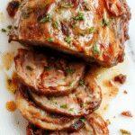 A tender, juicy chuck roast glazed with caramelized onions resting on a rustic wooden surface, garnished with sprigs of thyme and surrounded by sliced onions and carrots, with the rich juices glistening under soft natural lighting.