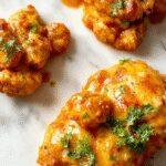 A vibrant plate of homemade butter chicken featuring tender chicken chunks coated in a rich, creamy orange sauce, garnished with fresh cilantro and served alongside fluffy white rice and colorful steamed vegetables, set on a rustic wooden table.