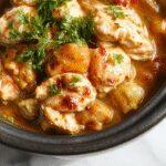 A hearty serving of slow cooker chicken stew in a rustic bowl, featuring tender chunks of chicken, vibrant orange carrots, green peas, and diced potatoes immersed in a rich, golden broth, garnished with fresh herbs on a wooden table with a cozy autumn backdrop.