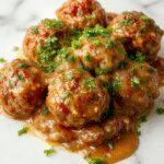 A hearty plate of Salisbury steak meatballs in a rich brown gravy, garnished with fresh parsley, served alongside buttery mashed potatoes and steamed vegetables. The dish is presented on a rustic wooden table with a side of crusty bread, showcasing a comforting and inviting family meal.