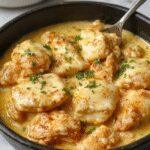 A sizzling skillet of honey butter chicken breast topped with a glossy, golden honey butter glaze. The chicken rests on a bed of melted butter sauce, garnished with fresh herbs, and served with vibrant, colorful sides. The dish is presented on a rustic wooden table, emphasizing its hearty and comforting appeal.
