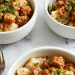 A vibrant rice bowl featuring seasoned ground turkey topped with a tangy, creamy bang bang sauce, garnished with chopped green onions and sesame seeds, served in a white ceramic bowl on a rustic wooden surface.